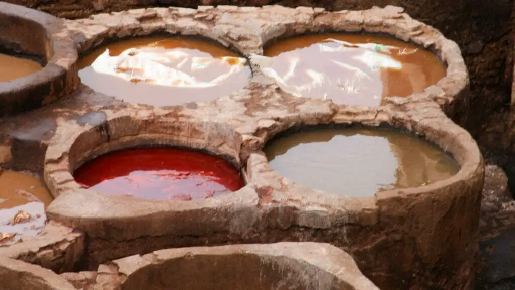 Traditional tannery in Morocco. Photo of several pits with dying tints and leather being dyed.