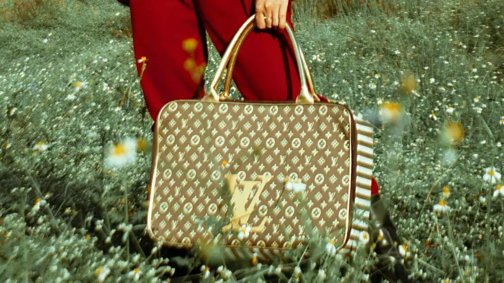 Photo of a woman with a Louis Vuitton handbag in the middle of a flower field.